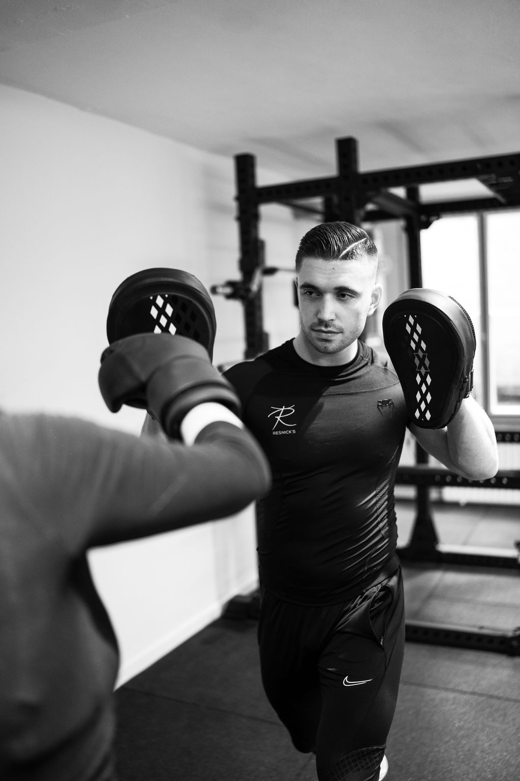 Jason holding boxing pads while coaching a client at Resnick’s studio